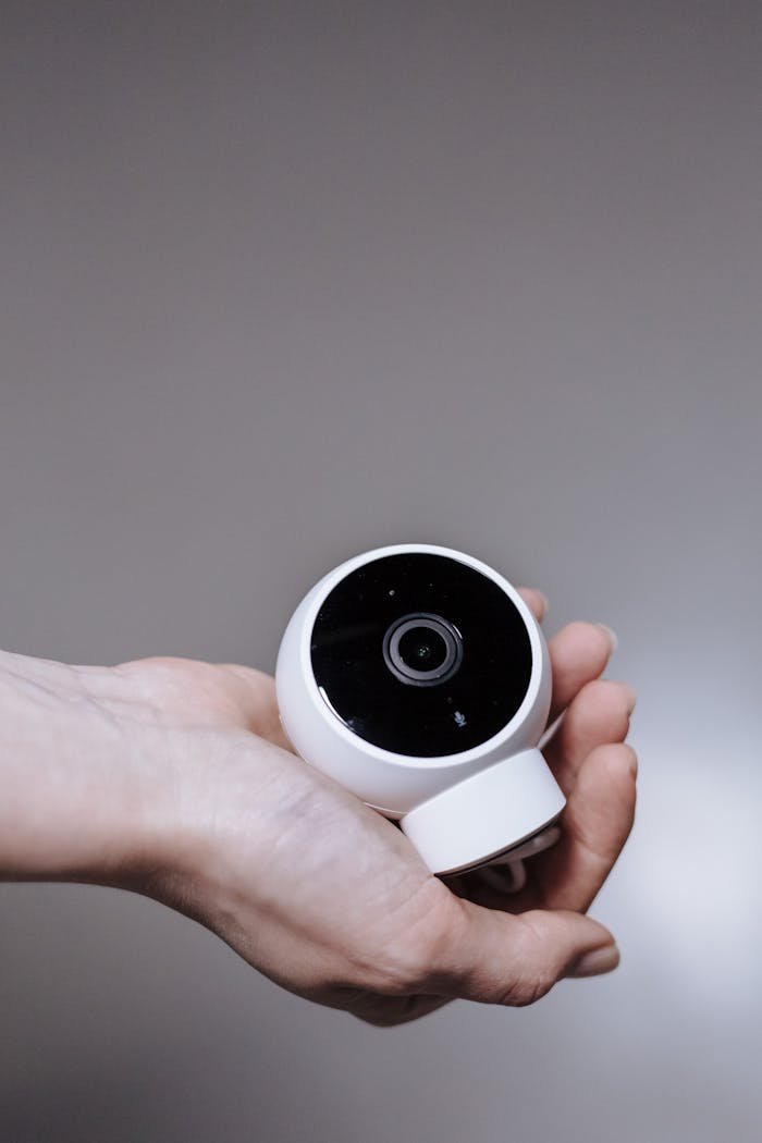 Smart home security camera held in a hand, showcasing modern technology in a minimalist style.